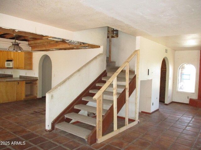 5716 E Desert Vista Trl, Cave Creek, AZ 85331 - stairs with arched walkways, baseboards, and a textured ceiling