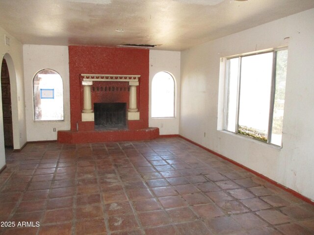 5716 E Desert Vista Trl, Cave Creek, AZ 85331 - unfurnished living room with arched walkways, a fireplace with raised hearth, baseboards, and tile patterned flooring