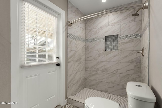 bathroom with tiled shower and toilet