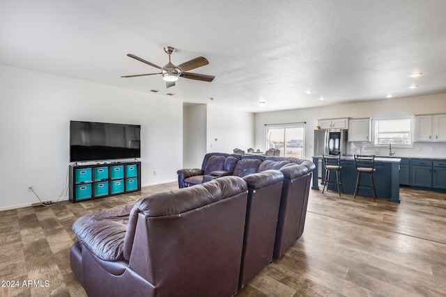 living room featuring sink, hardwood / wood-style floors, a textured ceiling, and ceiling fan