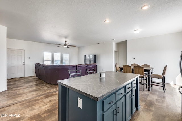 kitchen with a kitchen island, hardwood / wood-style flooring, a textured ceiling, and ceiling fan