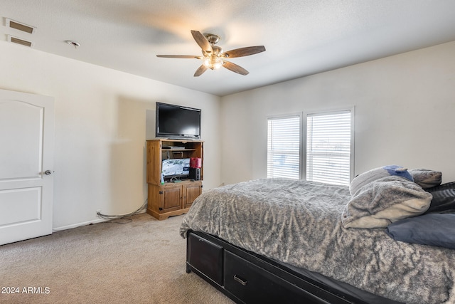 bedroom with ceiling fan, light carpet, and a textured ceiling