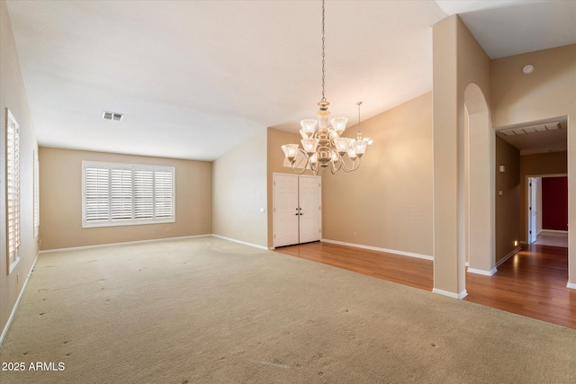 spare room featuring vaulted ceiling, carpet, and an inviting chandelier