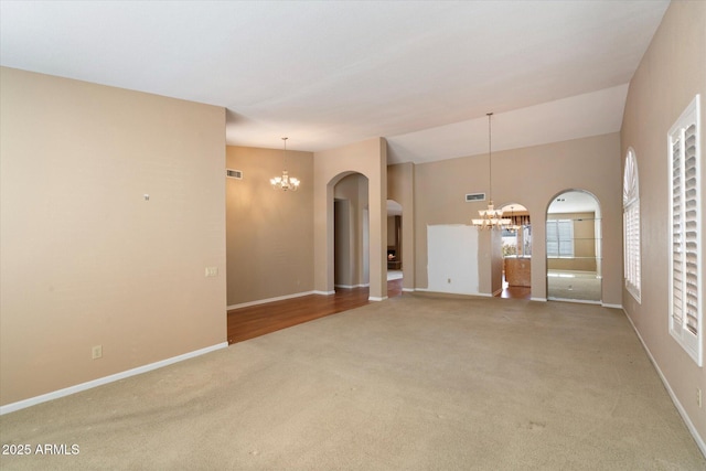 carpeted empty room featuring a chandelier