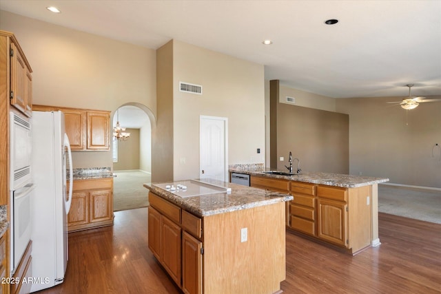 kitchen featuring sink, a center island, ceiling fan, light stone countertops, and white appliances