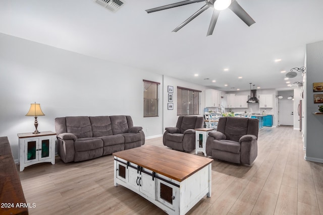 living room with ceiling fan and light hardwood / wood-style flooring