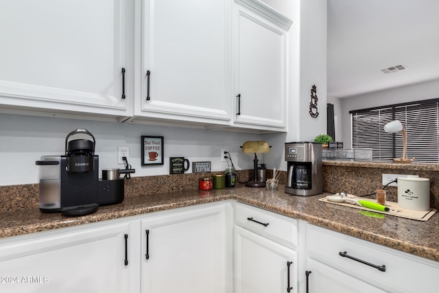 kitchen featuring white cabinetry and dark stone counters