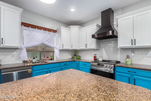 kitchen with white cabinetry, sink, stainless steel appliances, wall chimney range hood, and dark stone counters