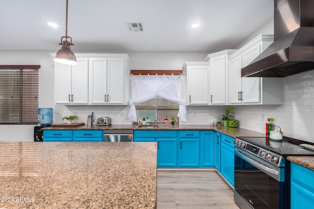 kitchen featuring wall chimney exhaust hood, sink, blue cabinetry, and appliances with stainless steel finishes