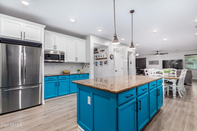 kitchen with pendant lighting, blue cabinets, appliances with stainless steel finishes, a kitchen island, and white cabinetry