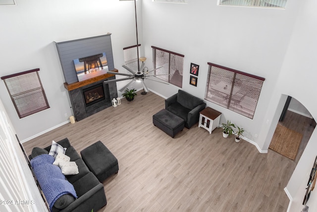 living room featuring ceiling fan, a towering ceiling, and light wood-type flooring