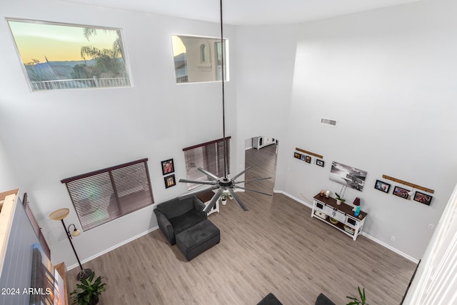 living room with ceiling fan, wood-type flooring, and a high ceiling