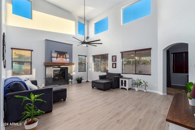 living room with ceiling fan, light wood-type flooring, and a high ceiling