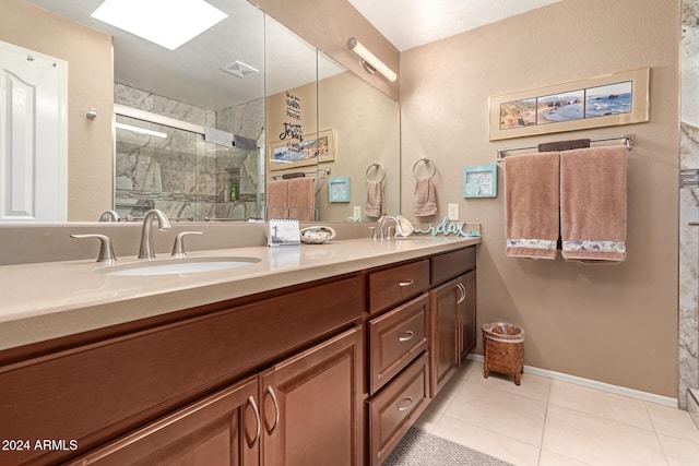 bathroom with tile patterned flooring, vanity, an enclosed shower, and a skylight