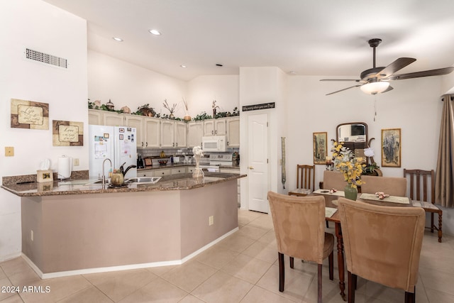 kitchen with kitchen peninsula, backsplash, white appliances, light tile patterned floors, and dark stone countertops