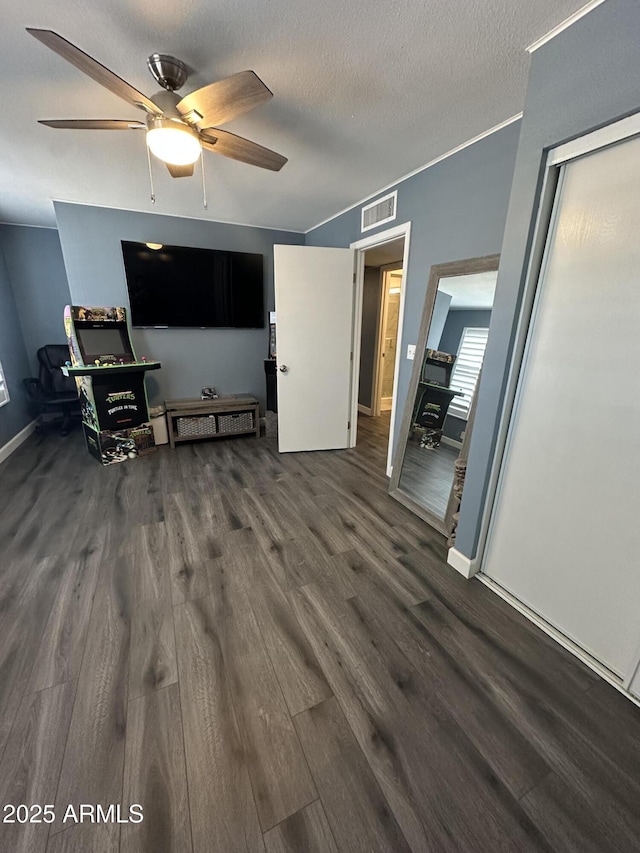 unfurnished living room with crown molding, ceiling fan, dark hardwood / wood-style flooring, and a textured ceiling