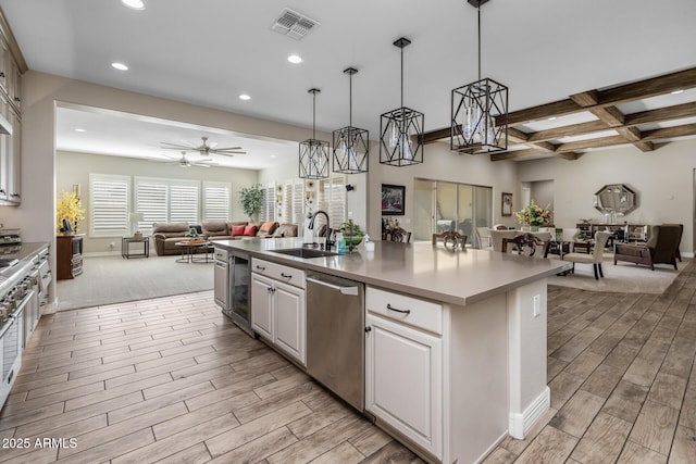 kitchen with sink, decorative light fixtures, a center island with sink, dishwasher, and white cabinets