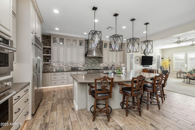 kitchen with a breakfast bar area, appliances with stainless steel finishes, backsplash, a spacious island, and decorative light fixtures