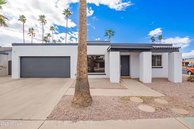 view of front of property featuring concrete driveway, an attached garage, and stucco siding