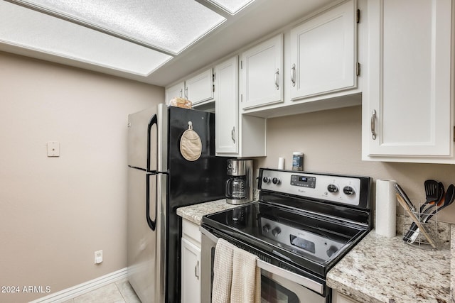 kitchen with appliances with stainless steel finishes, light stone counters, white cabinetry, and light tile patterned flooring