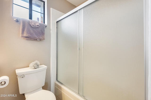 bathroom featuring enclosed tub / shower combo and toilet