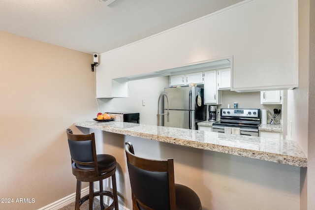 kitchen with kitchen peninsula, appliances with stainless steel finishes, a kitchen breakfast bar, light stone counters, and white cabinets