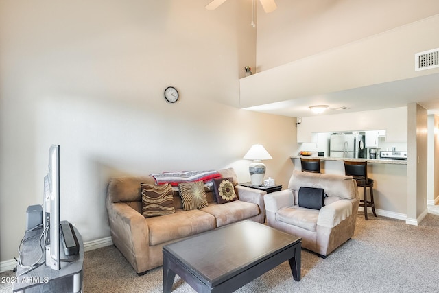 carpeted living room with ceiling fan and a high ceiling