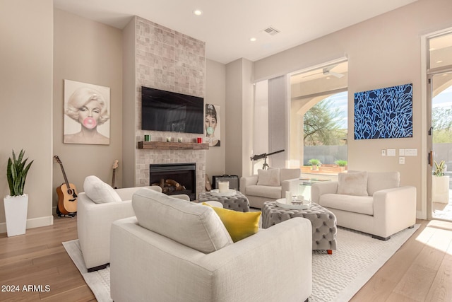 living room with a tile fireplace and light hardwood / wood-style flooring