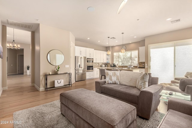 living room with a chandelier, light hardwood / wood-style floors, and sink