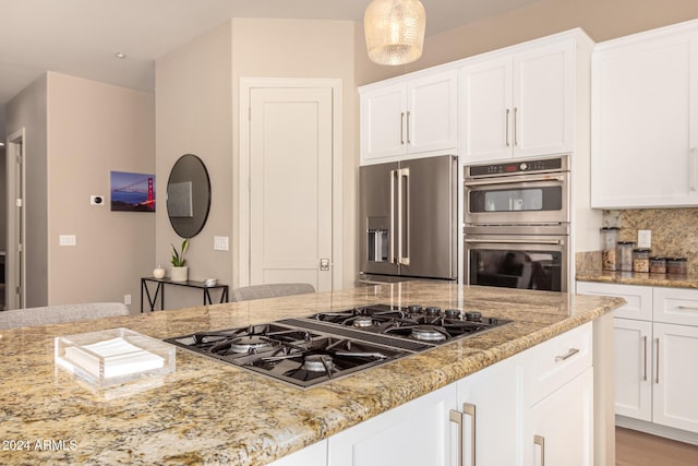 kitchen featuring light stone countertops, stainless steel appliances, and white cabinetry