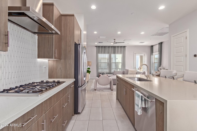 kitchen with wall chimney exhaust hood, stainless steel appliances, sink, decorative backsplash, and light tile patterned floors