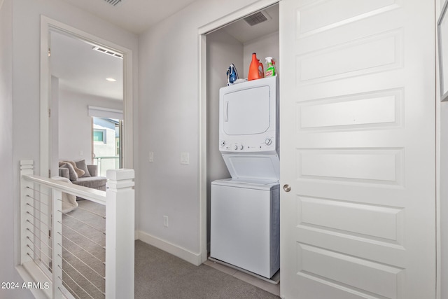 laundry area featuring stacked washer / drying machine and carpet flooring