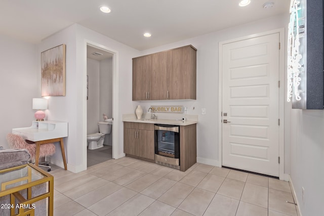 kitchen featuring beverage cooler, sink, and light tile patterned floors