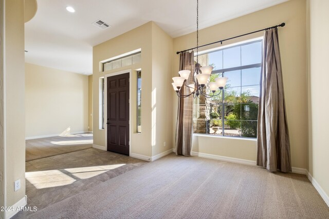 spare room featuring carpet flooring and a chandelier