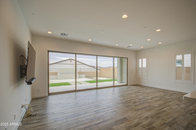 unfurnished living room featuring plenty of natural light, wood finished floors, visible vents, and recessed lighting