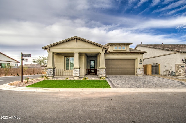 view of front of home featuring stone siding, fence, decorative driveway, a porch, and stucco siding