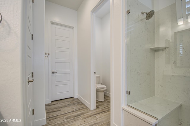 full bathroom featuring baseboards, a marble finish shower, toilet, and wood tiled floor