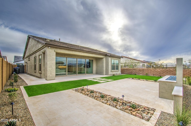 back of property featuring a fenced backyard, a patio, and stucco siding