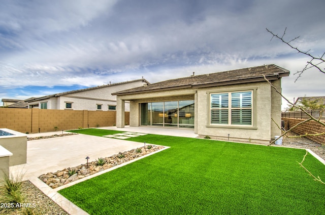 back of property featuring a yard, a fenced backyard, a patio, and stucco siding