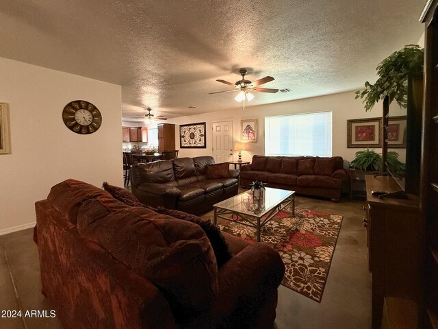 living room featuring ceiling fan and a textured ceiling