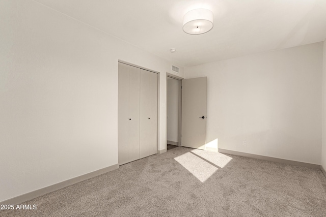 unfurnished bedroom with light colored carpet and a closet