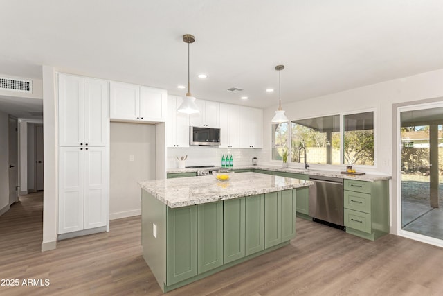 kitchen featuring pendant lighting, stainless steel appliances, green cabinetry, a kitchen island, and white cabinets