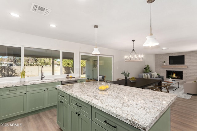 kitchen featuring light hardwood / wood-style floors, a kitchen island, green cabinets, sink, and a fireplace