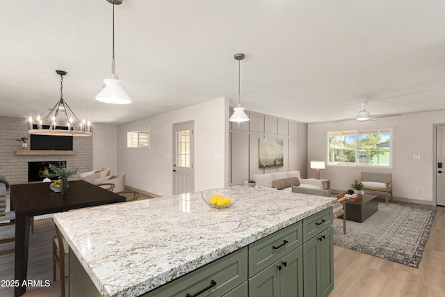 kitchen featuring a fireplace, ceiling fan, light hardwood / wood-style flooring, a kitchen island, and pendant lighting