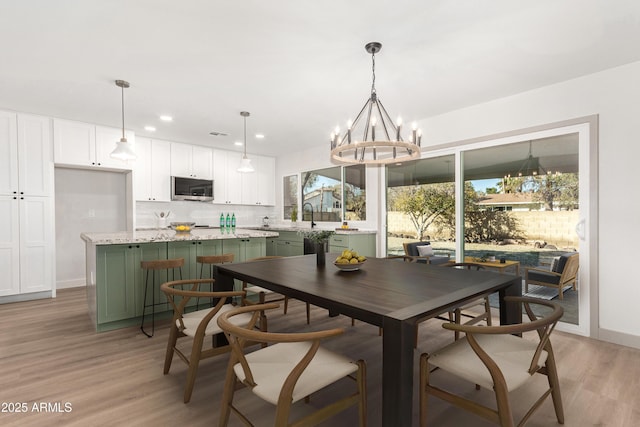 dining space with light hardwood / wood-style floors, a chandelier, and sink