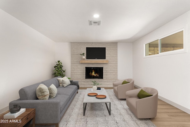 living room featuring a brick fireplace and light wood-type flooring