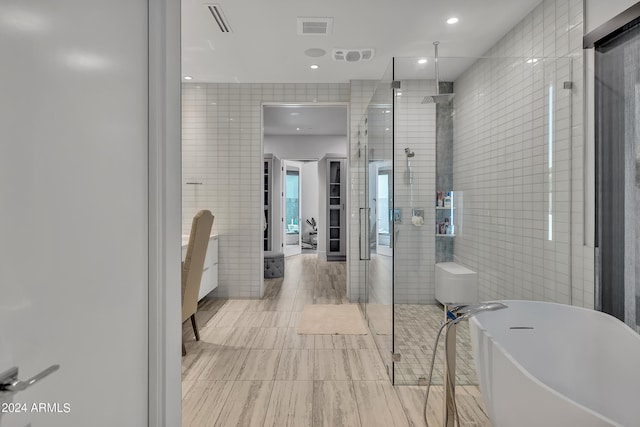 bathroom with tile patterned flooring, tile walls, and shower with separate bathtub