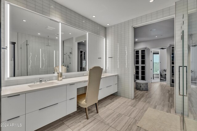 bathroom with vanity, tile walls, and a shower with shower door