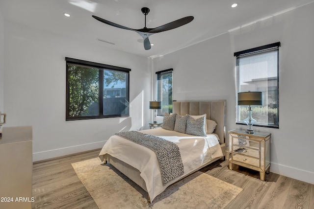 bedroom featuring ceiling fan, light wood-type flooring, and multiple windows