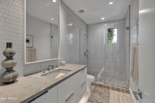 bathroom featuring toilet, a shower with door, vanity, backsplash, and wood-type flooring